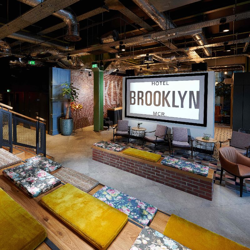 Stoop - To left of reception is The Stoop with ground floor seating plus stairs to 3 levels of benches Flatwood flooring to Stoop then low pile carpet. Well lit area & large screen TV with subtitles