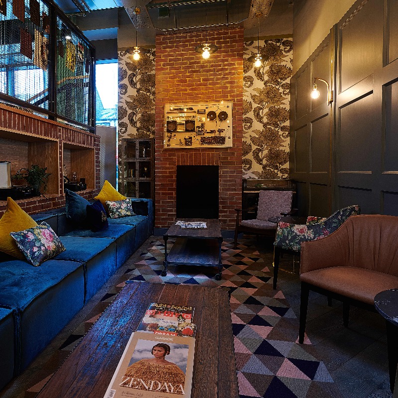 Snug/Quiet Area - Quiet Snug located between Stoop & Bar Area has reduced noise levels. Banquette seating & chairs with soft furnishing. Dimmed lighting and harlequin pattern, mid pile, carpet.