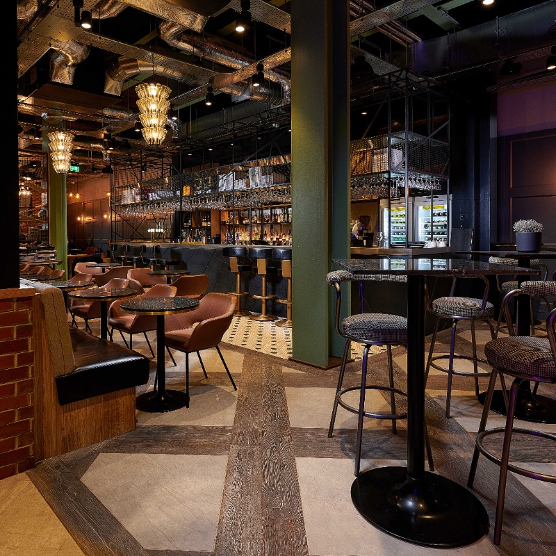 Runyon's Bar - Tables at wheelchair height mixed with high tables & bar stools. Flooring is flat & smooth & patterned contrast to main walkway. Lower bar area at wheelchair height for orders. Well lit & high ceilings. Can be noisy when full.