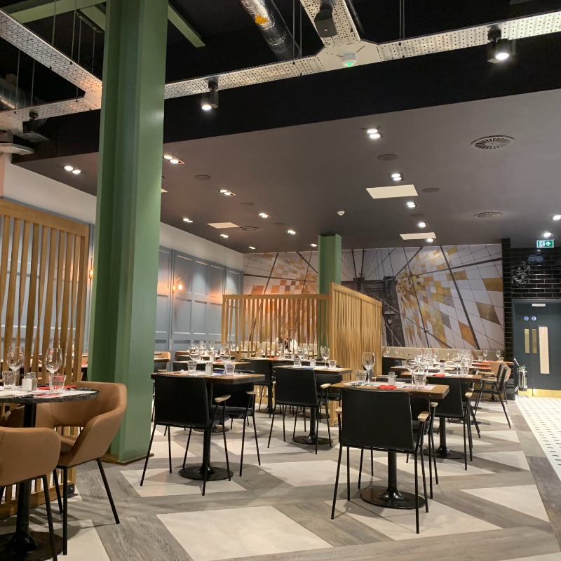 Runyon's Restaurant - Well Lit with industrial style high ceiling for good acoustics. Flooring flat & smooth with pattern for colour contrast with main walkway. Ground Floor disabled toilet opposite main walkway. Tables wheelchair height, no leg obstruction.